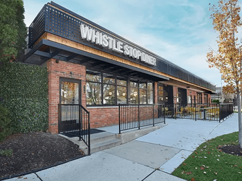 A whistle stop diner with a black awning and brick building